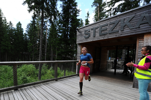 Horský půlmaraton Lipno. Závodnice vybíhá ze Stezky v korunách stromů. Horský půlmaraton Lipno.